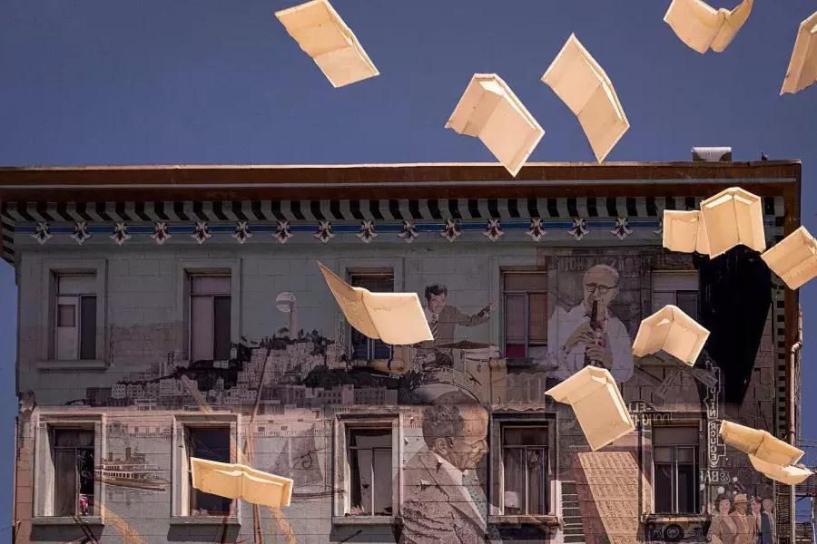 Toma exterior de la librería City Lights 在贝博体彩app, que muestra un mural de libros y papel flotante.